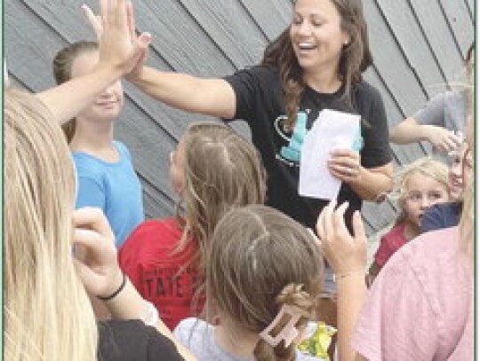 Riley Dohlen leads Studio 103’s Strength, Flexibility, Leaps and Turns Summer Camp earlier this month. Studio 103, owned by Chelsea Kuchta, is celebrating its 10th year in business. At right, Kuchta finds herself surrounded during the studio’s anniver