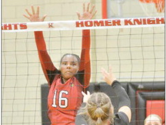 Jacey Bartels (above) of Randolph tips the ball over the net against Homer during triangular action last week. The Lady Cardinals fell in that match and the other against Cedar Catholic. Mabel Ngebeh (left) defends the net. The Lady Cardinals are struggli