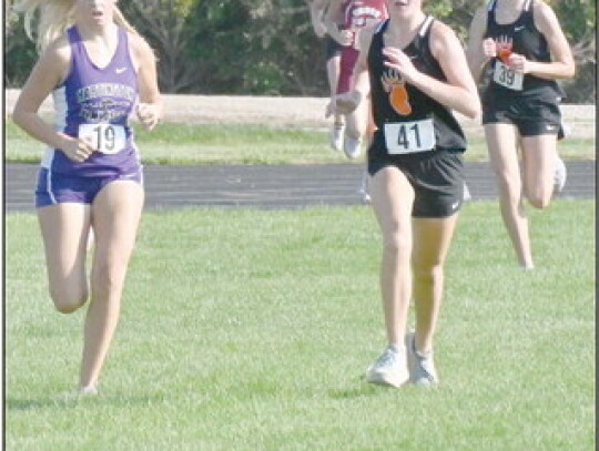 Isaac Hernandez-Santiago (top) started Thursday’s cross country meet near the front of the pack. He ended the day near the front, as well, finishing in 15th. Carmen Buschkamp (left) battles LCC’s Addison Hoeppner for 16th place as they approach the fi