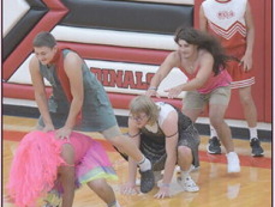 Friday’s pep rally brought the silly. Gage Jensen (above) starts a train of leap frog over Joe Gonzalez, Bryson Eledge over Shaw Baker, and Dalton Winkelbauer waiting his turn. Jake Harder (photo at left) positions a balloon for fifth-grader Emmett Junc