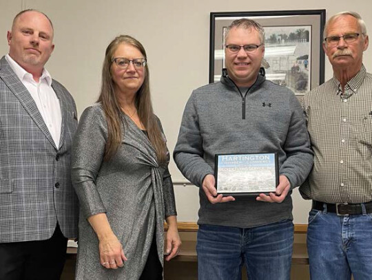 Hartington Chamber of Commerce Vice President Ray Sukovaty and President Karen Flamig present John Becker and Tom Becker with a plaque honoring the 75th anniversary of Becker Flying Service.