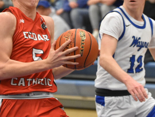 Cedar Catholic’s Nolan Becker concentrates on hanging onto the ball as he heads to the basket during action Saturday at West Point. The Trojans defeated Wayne in the contest to earn the third-place trophy in the annual MidStates Conference Tournament. M