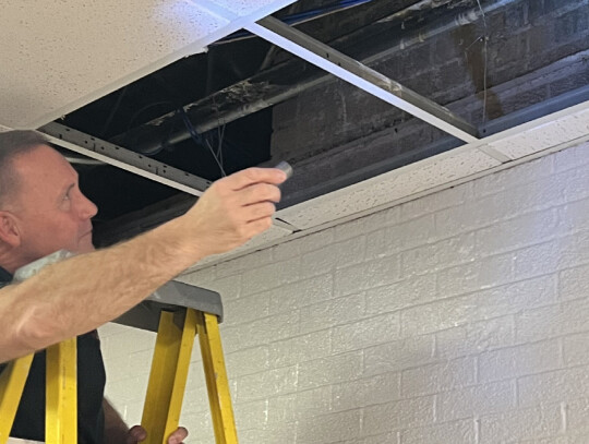 School Board Vice President Jim Scott shines a light on the condition of a portion of Randolph High School’s ceiling during a facilities tour Monday night. Roof damage has caused leaking and other issues. Trisha Benton|Randolph Times