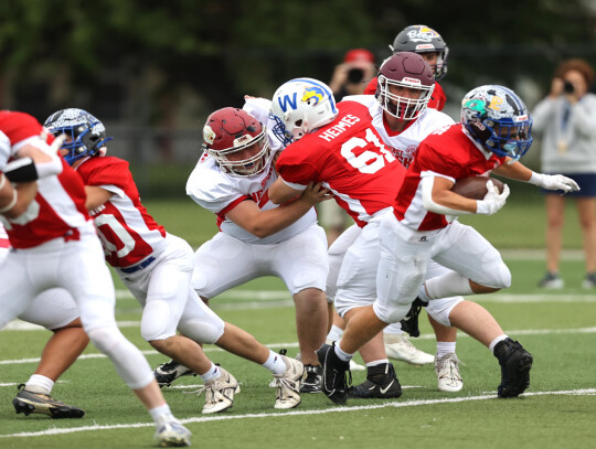 Cedar Catholic’s Andrew Heimes blocks as his Red Team running back tries to get around the line during action in Saturday’s contest at Memorial Field in Norfolk.