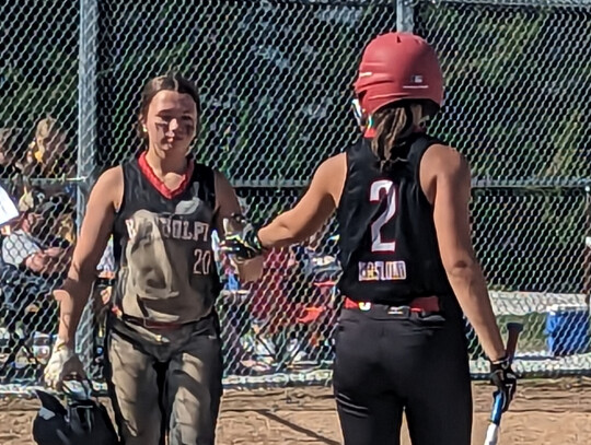 With a full front of dirt, Lilly Kuchta gets a high five from teammate Emma Naslund during tournament action at Laurel.