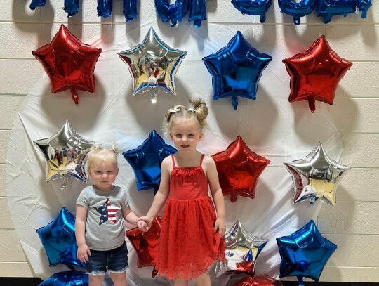 Children at the Cardinal Kids Learning Center got in on some holiday activities last week. At left, Brooklyn Walsh shows off rocks painted in red, white and blue. At right, Emry and Drew Backer pose in front of a holiday backdrop. Courtesy Photos